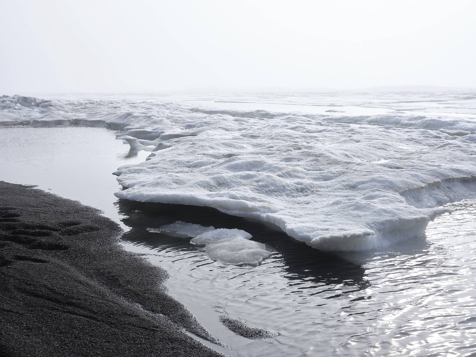 The Arctic ocean coast outside Barrow. Black sand beach with ice floating in the water